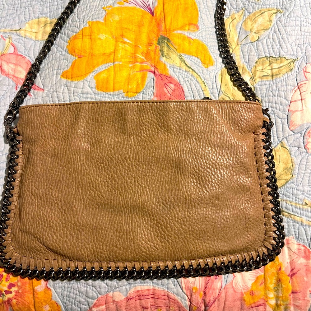 Carlos Santana crossbody with chain strap and surrounding detail.